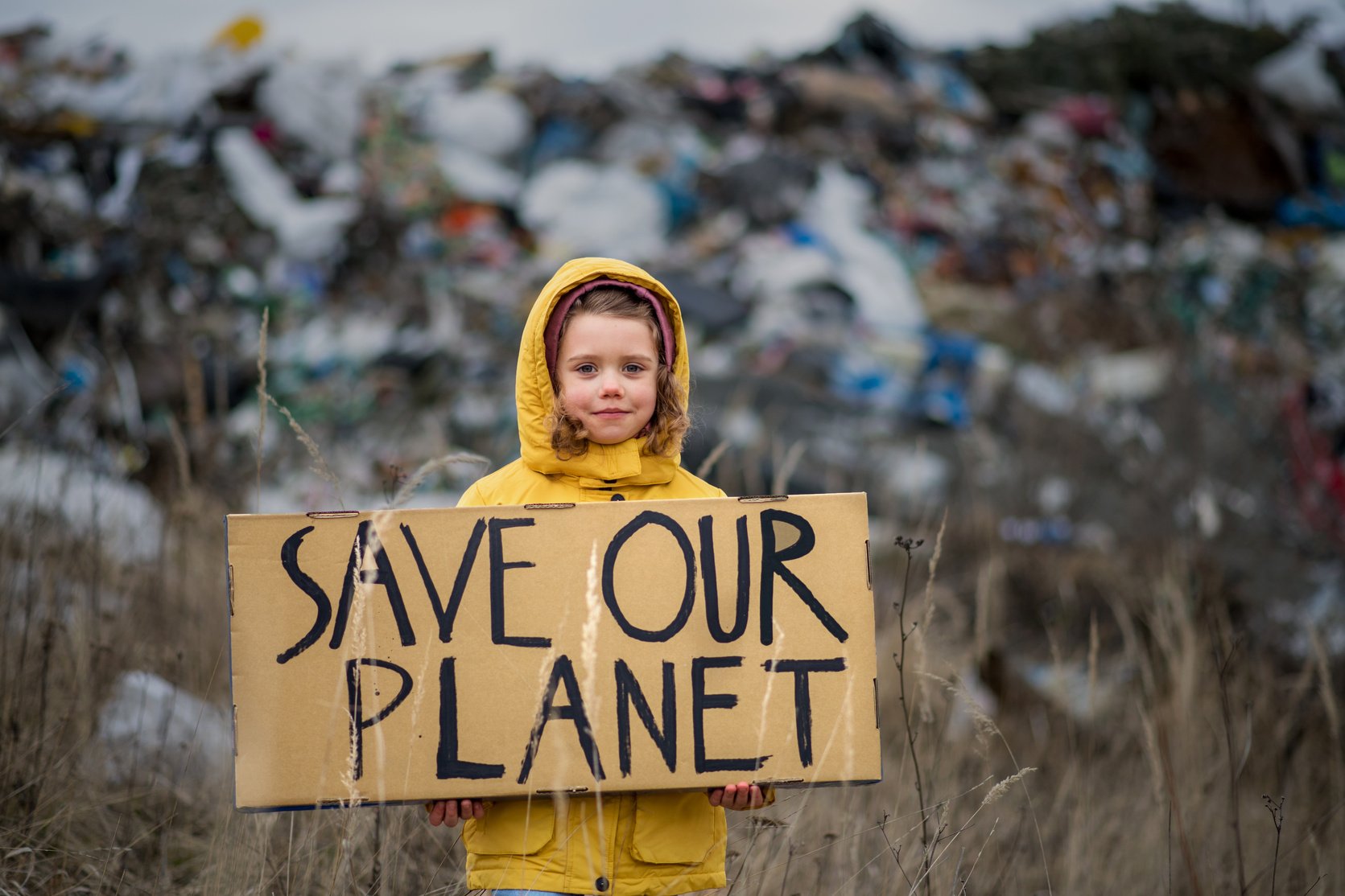 Small Child Holding Placard Poster on Landfill